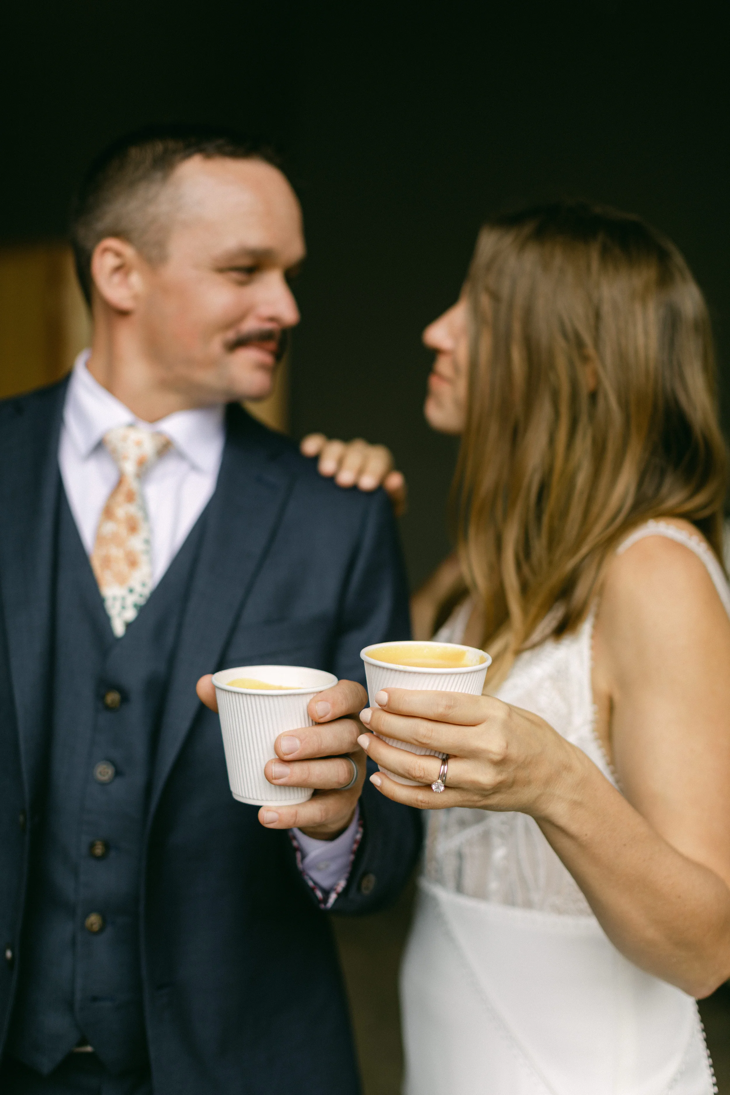 Couple in formal attire holding coffee cups at a Portland wedding